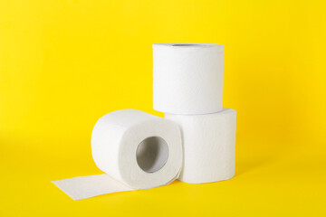 Many soft toilet paper rolls on yellow background