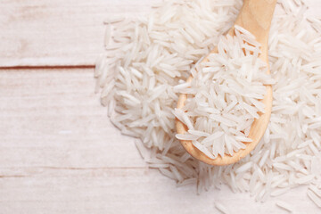 Raw basmati rice and spoon on white wooden table, top view. Space for text