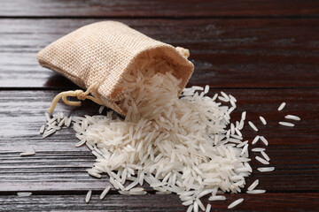 Raw basmati rice and bag on wooden table