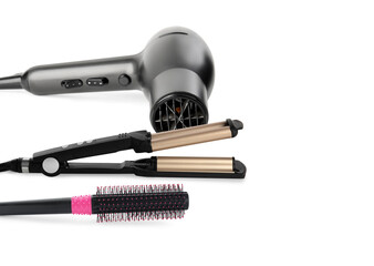Hair dryer, triple curling iron and round brush on white background