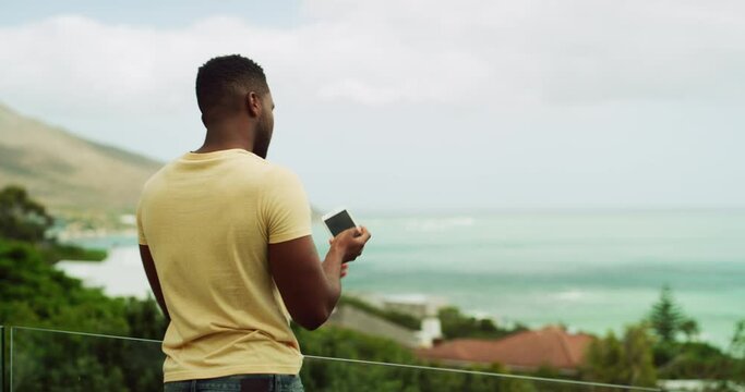 Man, phone and picture of ocean on balcony for holiday, scenery or vacation in summer accommodation. Black person, smartphone and photography of beach, view and tourist outdoor in nature for travel