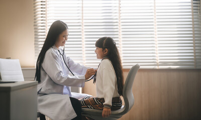 Southeast asian doctor woman using stethoscope check little girl health care in kid clinic...
