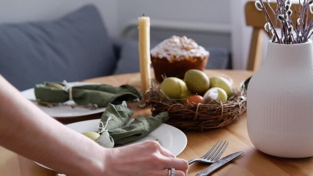 Festive dinner table setting for Easter. A woman puts cutlery on the festive table