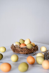 Close-up of a nest of twigs inside with yellow, green and light green easter eggs