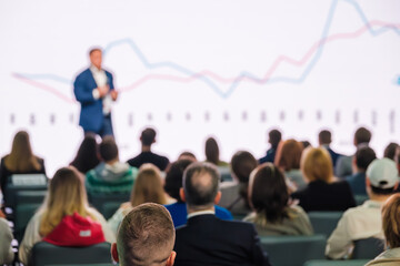 Blurred view of a business speaker at conference giving a presentation. Corporate executive delivering a speech. Audience engagement.