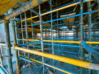 Scaffolding at the construction site of a multi-storey building. construction site with scaffolding and building materials, blue sky background