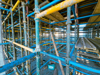 Scaffolding at the construction site of a multi-storey building. construction site with scaffolding and building materials, blue sky background
