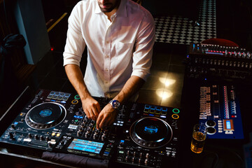 Crop DJ plays live set and mixing music on turntable console in the night club. Disc Jokey Hands on...