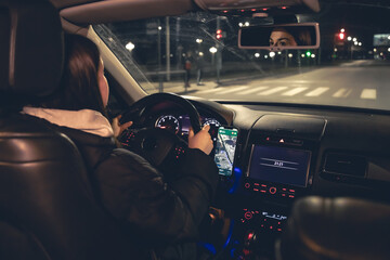Driving a car at night, a woman driving her modern car at night in the city.
