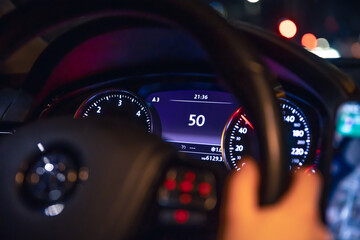 Speed indication and women's hands on the steering wheel in a car at night.