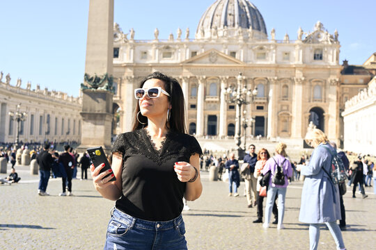 Rome,Italy, Vatican City, Rome, Saint Peter's Basilica in St. Peter's Square  Young beautiful woman  using a mobile phone taking a pictures.Concept of Italian gastronomy and travel