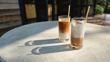 A glasses of milk coffee on cement table outdoor with sunlight. Summer drink