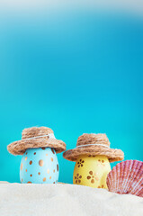 Yellow and blue eggs with polka dot in hat with conch on beach by sea on sunny day. Easter, travel,...
