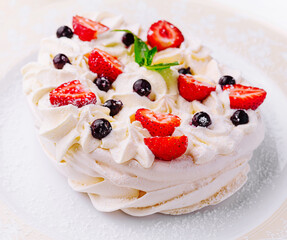 Pavlova cakes with cream and fresh berries on plate