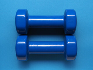 Two blue dumbbells on a blue background