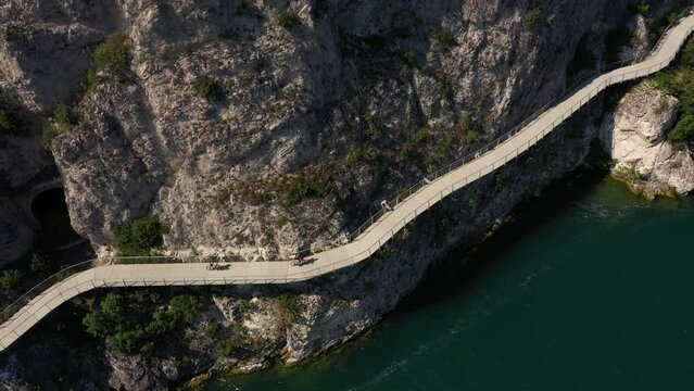 Garda bike path. Bicycle/pedestrian path Garda suspended above the lake. Alley of Limone sul Garda. Section of the longest cycle path in Europe 4K aerial view. 