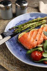 Tasty grilled salmon with tomatoes, asparagus, spinach and lemon served on table, closeup