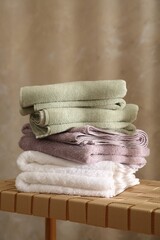 Fototapeta na wymiar Stack of soft towels on wicker bench indoors