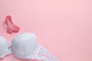 Pink ribbon and bra on color background, top view with space for text. Breast cancer awareness