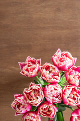 Pink fresh tulips on a wooden table, top view.
