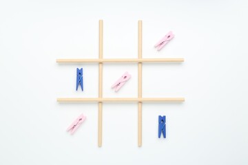 Tic tac toe game made with clothespins on white background, top view