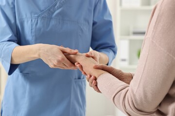 Obraz na płótnie Canvas Arthritis symptoms. Doctor examining patient's wrist in hospital, closeup