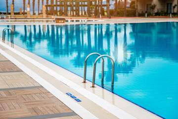 Swimming pool with stair and blue water close-up with copy space