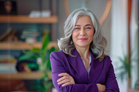 Happy middle aged business woman ceo standing in office arms crossed. Smiling mature confident professional executive manager, proud lawyer, businessman leader wearing violet suit
