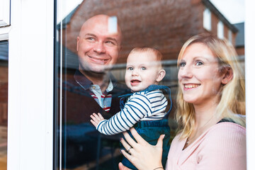 Happy family portrait, smiling and looking through the window