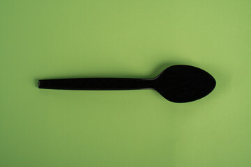 Black plastic spoon isolated on green background