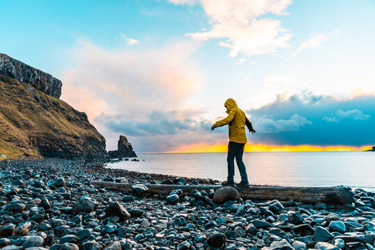 Man hanging in the balance over a log at seaside in Scotland