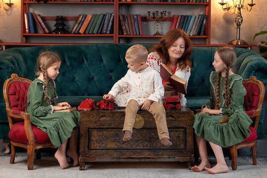 Happy grandma and grandchildren reading book together and having fun at home