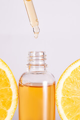 Ultra hydrating facial Vitamin C Serum Ad, Dropper bottle over sliced orange on white background. Skincare concept.