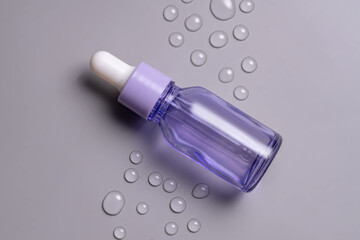 Transparent violet cosmetic bottle with pipette on grey background with water drops, product packaging, anti aging serum with peptides, hyaluronic cosmetics mockup, spa concept