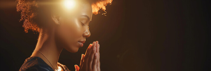 African American woman prays to god on dark studio background. Cinematic effect