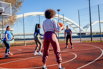 Diverse group of young woman having fun playing recreational basketball outdoors.