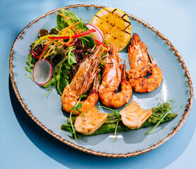 shrimps with boiled asparagus on blue plate