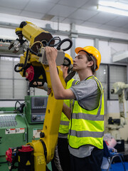 Robot maintenance engineer working on robot arm connection. Young adult man learning training...