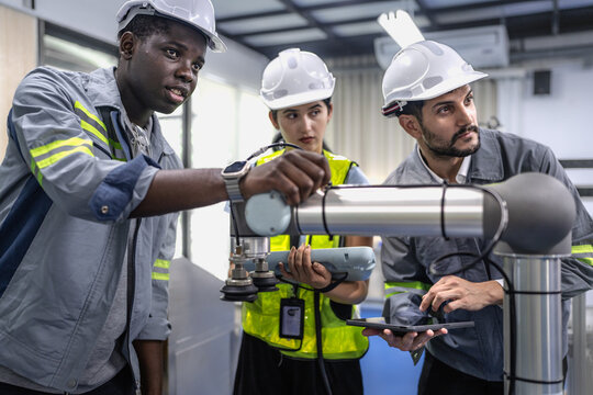 Group of diverse people working on robot programming in robotic and electronic engineering laboratory. Engineer team learning and research automated project machine with intelligent mechanical control