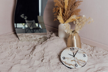 Round wall clock. Clock hands and dial. On the sand.