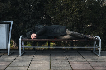 lonely man homeless and upset lies sleeping on a park bench
