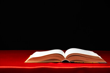 Open book on red and black background. The wisdom of generations, knowledge and love of reading, a place for text.