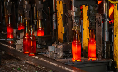 Glass factory, production of glass containers. Molten glass is blown into molds. Robotics in industry. Modern technologies, robotic machines produce products. Technological work at the plant.