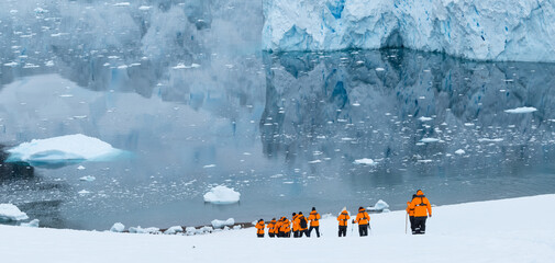 Unrecognizable cruise tourists hiking in the snow during expedition in Neko harbor, Antarctica.