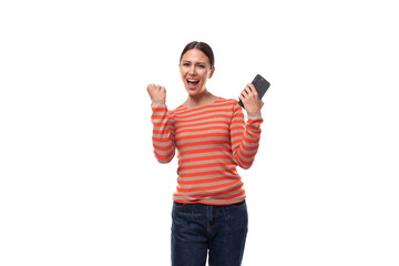 young adult woman dressed in an orange striped sweater rejoices in good luck holding a phone