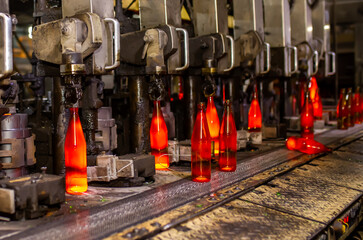 Glass factory, production of glass containers. Molten glass is blown into molds. Robotics in industry. Modern technologies, robotic machines produce products. Technological work at the plant.