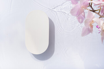 Podium or pedestal of water ripples and orchid flowers lying flat, top view. Summer cosmetic template, mockup