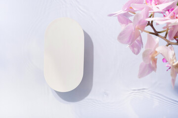 Empty podium or pedestal of water ripples and orchid flowers top view. Summer cosmetic template