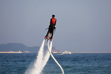 Flyboarding on a sea. Man with a child riding on a fly board