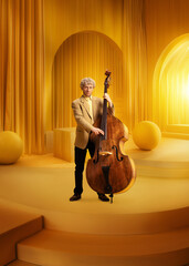 Male musician in suit with double bass in monochromatic yellow luxurious room. Elegance and classical taste. Concept of music, performance, art, talent show, inspiration. Poster